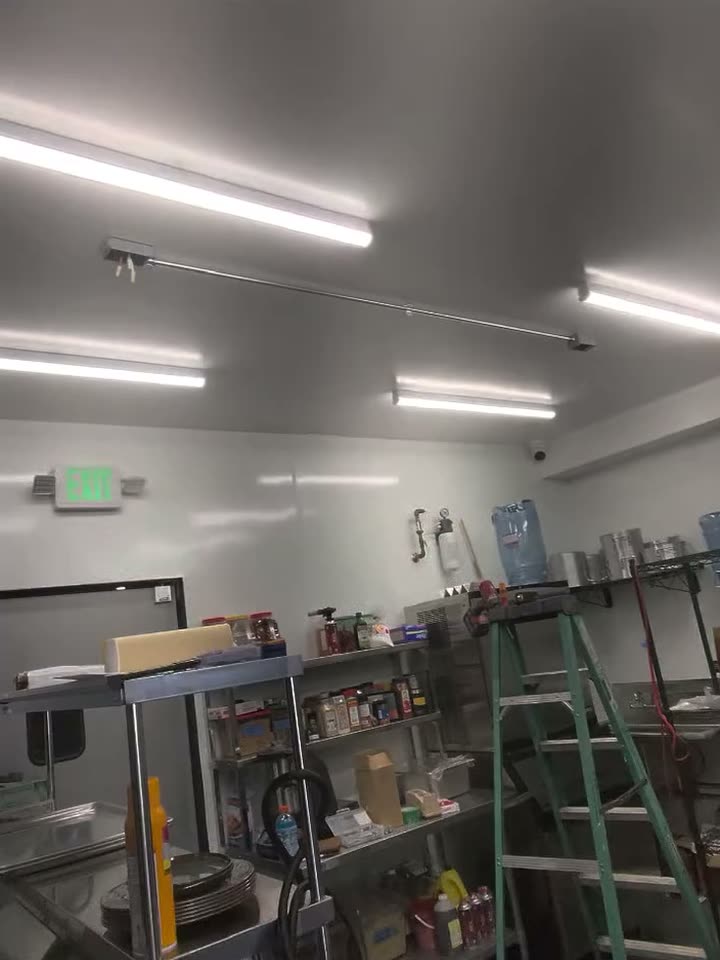 Long LED strip lights installed across a commercial space, an exit sign on the far wall.